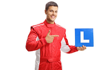 Smiling young racer holding a learner plate and pointing