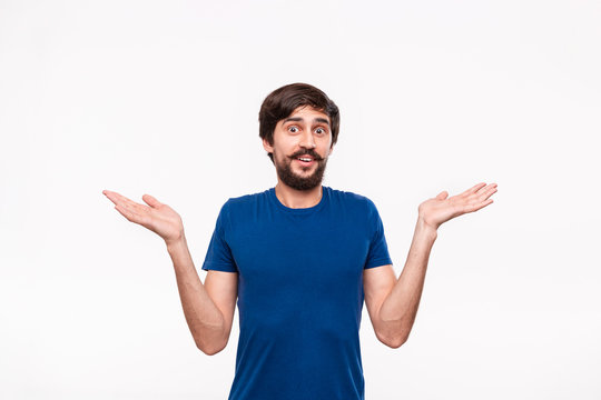 Good looking bearded brunet man with mostaches in a blue shirt shrugging shoulders with sceptical emotion standing isolated over white background.