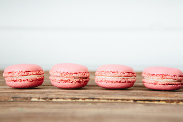 Sweet colorful French macaroon cookies dessert on brown wooden table over white wooden background