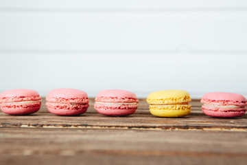 Sweet colorful French macaroon cookies dessert on brown wooden table over white wooden background
