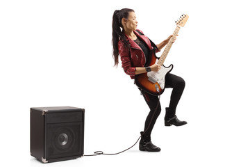 Female guitarist playing a guitar plugged in an amplifier