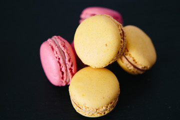 Sweet colorful French macaroon cookies dessert over black background