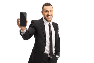 Young man in a suit showing a mobile phone and smiling