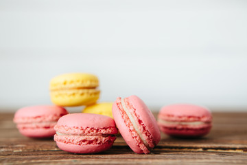 Sweet colorful French macaroon cookies dessert on brown wooden table over white wooden background