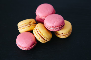 Sweet colorful French macaroon cookies dessert over black background