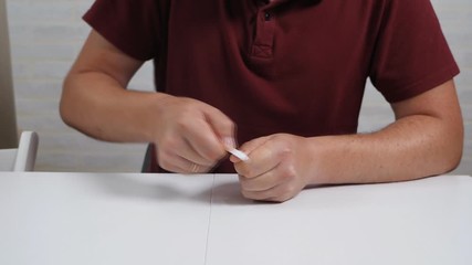 A bald man sits at a table and looks after his nails. Nail file