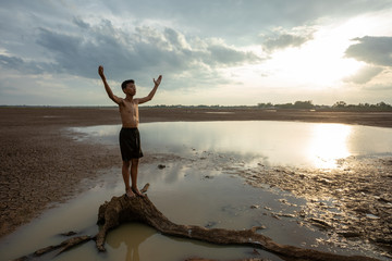 Sad boy praying for the rain on cracked dry ground , Concept drought and shortage of water crisis, selective and soft focus © bunyarit