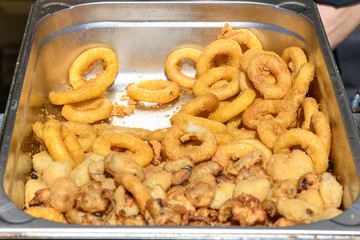 Large group of freshly fried calamari rings and mussels on display for sale at a street food festival, ready to eat seafood 