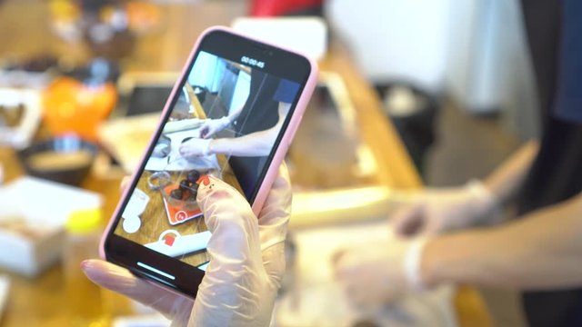 Woman shoots a video of a culinary master class on a smartphone