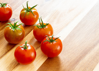 Small fresh and red tomatoes with green stem on wood background