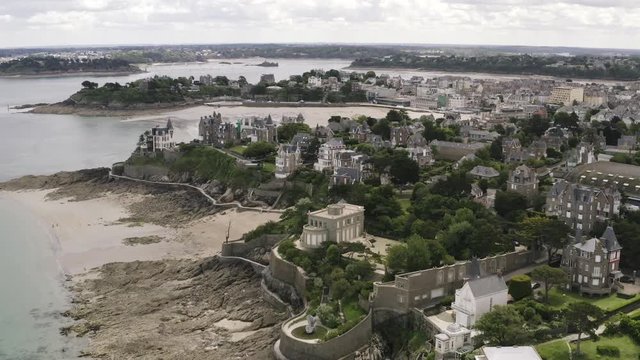 Contrast aerial view of grey old European city and bright green vegetation near the river in summer against grey cloudy sky. Action. Beautiful European architecture