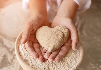 Heart shaped dough for bread cooked by mother and child