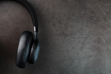 Fototapeta na wymiar Black bluetooth headphones on a dark background with blue and orange backlight. In-Ear Headphones for DJs