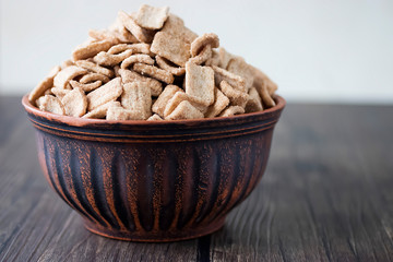 Whole grain cinnamon flakes in a brown bowl. Breakfast cereals. The concept of a quick and healthy breakfast.