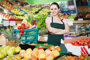 salesgirl in store with basket filled with fresh fruits and vegetables