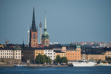 Obraz premium Stockholm buildings at the bay Riddarfjärden between the district Södermalm, Kunsholmen, Gamla Stan and Riddarholmen at sunset with a low sun and fogg torning up in the archipelago