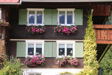 Altes Haus mit sommerlichem Blumenschmuck, alpine Architektur in Europa, Haus in der europäischen Alpenregion mit traditionellem Blumenschmuck