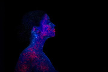 Profile portrait of a beautiful girl alien. Ultraviolet body art blue night sky with stars and pink jellyfish, 