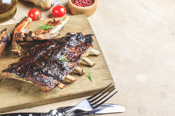 Delicious barbecued ribs seasoned with bbq sauce on rustic wooden chopping board.