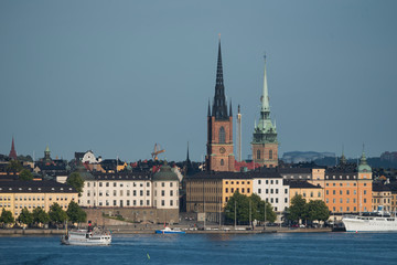Fototapeta premium Stockholm buildings at the bay Riddarfjärden between the district Södermalm, Kunsholmen, Gamla Stan and Riddarholmen at sunset with a low sun and fogg torning up in the archipelago