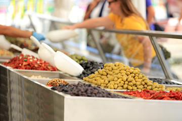 Klient degustuje oliwki na straganie, w markecie, na rynku miasta Wocław.