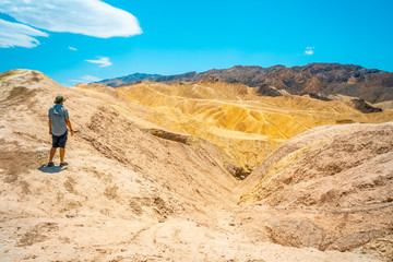 Panoramic of a young man enjoying the view of the Zabriskie Point viewpoint, California. United States