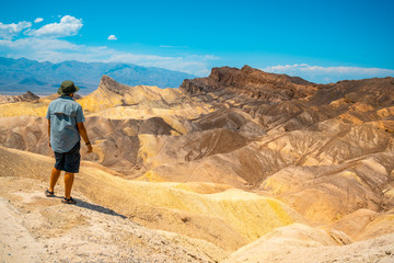 Fototapeta na wymiar A man with a green shirt on the beautiful viewpoint of Zabriskre Point, California. United States
