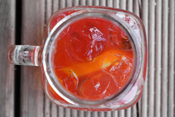 summer soft drink of fresh fruits and berries, cold mineral water, ice and mint in glass with handle.