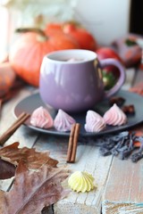 Cup of coffee, meringues, pumpkins, leaves, plaid on a window background, home comfort concept, Thanksgiving, autumn season