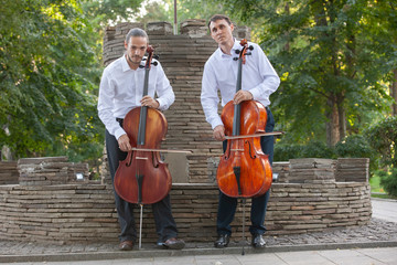 Cellist musician group perform music in the street, close up man playing violin