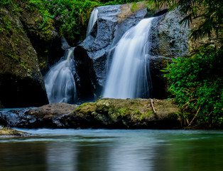 Soft motion waterfall in the river with green grass. Long exposure photography