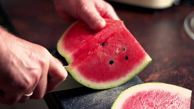Closeup of male hands cutting watermelon on the board, slow motion