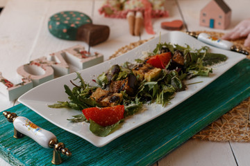 stewed zucchini and tomatoes with herbs on a white plate with a green stand