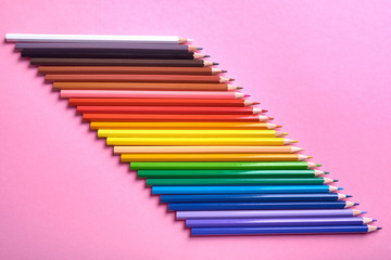 Color pencils on pink pastel background, close up. Set of colorful pencils, copy space. Crayons. Top view, flat lay. Back to school, college concept. Abstract background