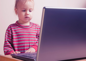 Humorous photo of little cute child girl programmer working with laptop