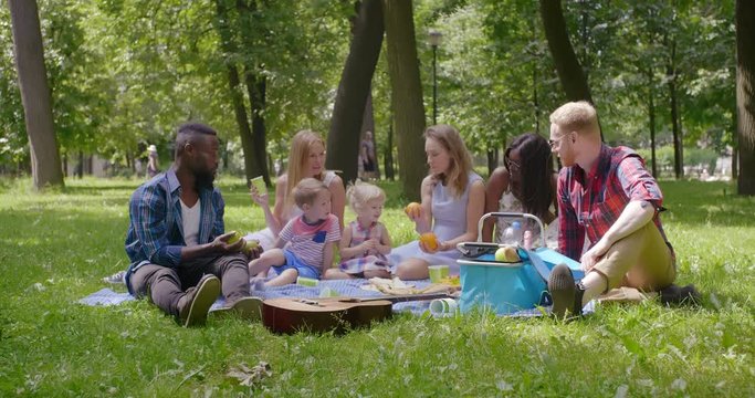 Mixed race people playing with children at park
