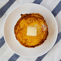 Homemade corn meal Johnny cakes with butter on a white plate, view from above. Flat lay, overhead, top view. Close-up.