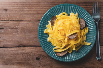 Italian cuisine- tagliatelle with black truffle on rustic plate.
