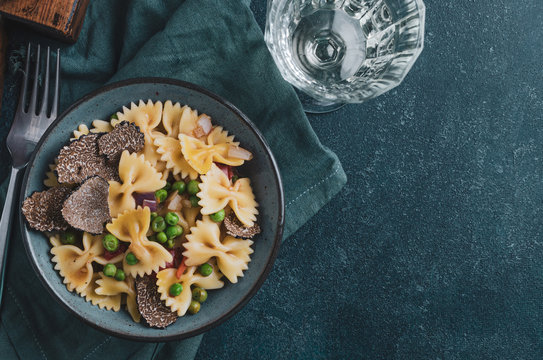 Pasta with black truflle and green peas in blue bowl.