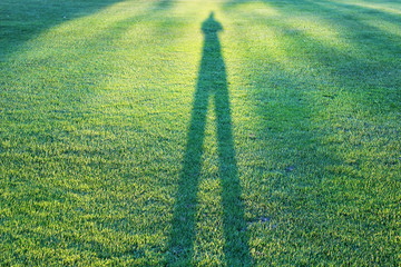 man shadow on grass field on sunny day