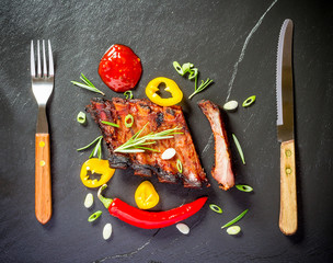 Grilled spareribs on slate plate with cutlery