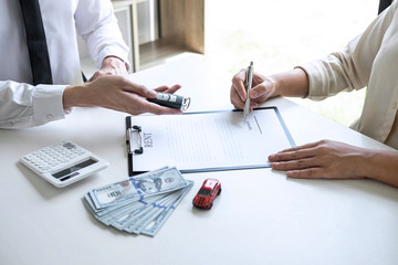 Car rent agent manager holding key of new car giving to woman client after signing good deal agreement contract, renting considering vehicle