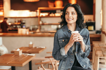Positive casual woman drinking coffee alone at cafe