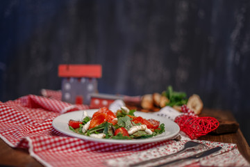 tomatoes, peppers and greens on a white plate and slices of bread with herbs on a wooden tray