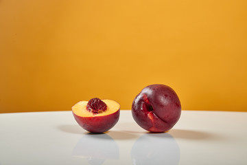 Two beautiful, ripe, juicy nectarines lie on a white table behind