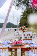 Romantic dinning table on the beach . Table setting at a luxury wedding and Beautiful flowers on the table. dinner table on the sand beach.