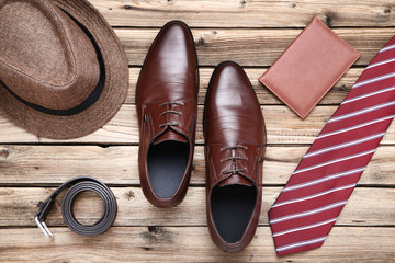 Male leather shoes with passport and accessories on brown wooden table