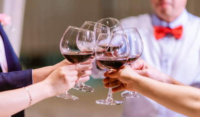 Clinking glasses above dinner table. Hands of people with glasses. Hands of people with glasses of champagne or wine, celebrating and toasting in honor of the wedding or other celebration.