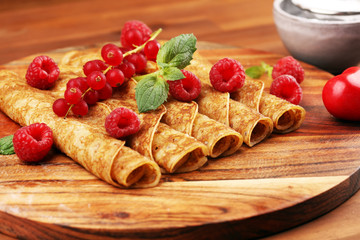 Delicious Tasty Homemade crepes or pancakes with raspberries and mint on rustic background