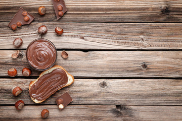 Bread with melted chocolate and hazelnuts on brown wooden table